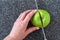 Woman slicing a green Granny Smith apple on a plastic man made faux gray granite cutting board, hands and chefs knife