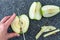 Woman slicing a green Granny Smith apple on a plastic man made faux gray granite cutting board, hands and chefs knife, apple half