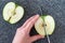 Woman slicing a green Granny Smith apple on a plastic man made faux gray granite cutting board, hands and chefs knife, apple halve