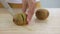 Woman is slicing kiwi fruit  on wooden cutting board