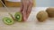 Woman is slicing kiwi fruit  on wooden cutting board