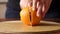 Woman slicing orange on wooden board. Close-up.