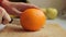 Woman slicing orange on wooden board. to make fresh smoothie