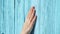 Woman slide hand against blue-colored wooden door in slow motion. Female hand touch surface of wood