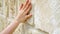 Woman sliding hand against old stone wall in slow motion. Female hand touching rough surface of rock