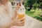 Woman with slim figure drinks freshly squeezed orange juice from a plastic cup. Useful and harmful beverages