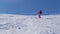 Woman slowly rolls down the mountain skiing on a steep slope with boulders