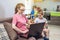 Woman with a small child on knees is sitting at a laptop. Remote work and receiving online education of home