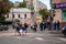 Woman with a small child are running along the crosswalk. Mom holds the girl by the hand. Cars ride on the road