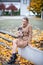 Woman with small dog among autumn leaves