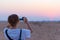 Woman smart phone photo at desert sunset. Tourist photographing the Namib desert, sunset romantic sky, travel destination in Namib