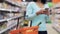 Woman with smartphone and food basket at shop