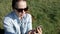 A woman with a smartphone in her hand is sitting in a Park on the grass