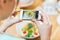 Woman with smartphone taking picture of food