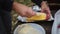 A woman smears corn with oil and spices to bake in foil over a fire. Hands and corn close-up