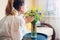 Woman smells bouquet of blue and yellow flowers on table at home. Interior with Ukrainian colors