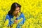 Woman smells flower in yellow rapeseed field