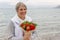 Woman with smile is pleased with the presented bouquet of flowers and fruits