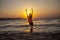 The woman smiles and standing with arms up at the beach during beautiful sunrise. Freedom and relax concept