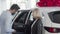 Woman smiling to the camera while her husband examining inside of a new car