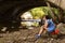 Woman smokes while sitting alone under a bridge