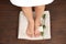 Woman with smooth feet, flower and towel standing on wooden floor, top view. Spa