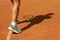 Woman in sneakers clay court with tennis ball