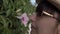 Woman sniffing flowers on a fence in the street close up