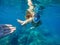 Woman snorkeling in blue mask near coral reef