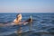 Woman snorkeling with little girl in her back with diving glasses in the water of a beach in Andalusia