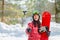 Woman with the snowboard using smartphone on a stick to making selfie