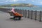 Woman, snuggled in sun lounger covered by plaid blanket. Cold autumn day on the beach