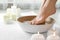 Woman soaking her feet in dish indoors, closeup with space for text.