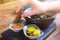 Woman soaks croutons in sauce at a table in a summer cafe, female hand close-up