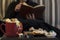 Woman on sofa reading a book with Halloween snacks and treats on table