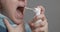 A woman with a sore throat sprays medicine aerosol spray down her throat