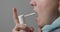 A woman with a sore throat sprays medicine aerosol spray down her throat