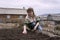 The woman sows the seeds in the ridge in the garden, against the background of the village.