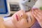 Woman in a spa salon on cosmetic procedures for facial care. Cosmetologist making a woman a therapeutic laser processing on a face