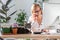 Woman speaking on phone, using calculator to calculate the invoice, working on desktop from home, cat sitting on the table