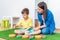 A woman speech therapist deals with a boy and performs an exercise to correct the speech apparatus by playing on the floor