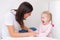 Woman speech therapist helps cute girl to learn correct pronunciation and literate speech