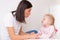 Woman speech therapist helps cute girl to learn correct pronunciation and literate speech