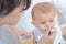 Woman spoon feeding baby from plastic pot food