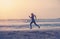 Woman in sports uniform runs along the ocean shore at dawn sunset, jogging active healthy lifestyle