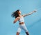 Woman in sportswear doing intense training with a resistance band. Slim female in sportswear exercising on blue background