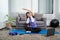 Woman in sportswear is sitting on a mat to do yoga exercise in the indoor living room at home, relaxing and healthy concept