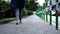 Woman in sporty pants walks along narrow asphalt sidewalk