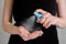 Woman spraying antiseptic on hands - close up, front view - spray disinfection