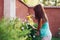 woman spraying with aphid repellent liquid on flowers